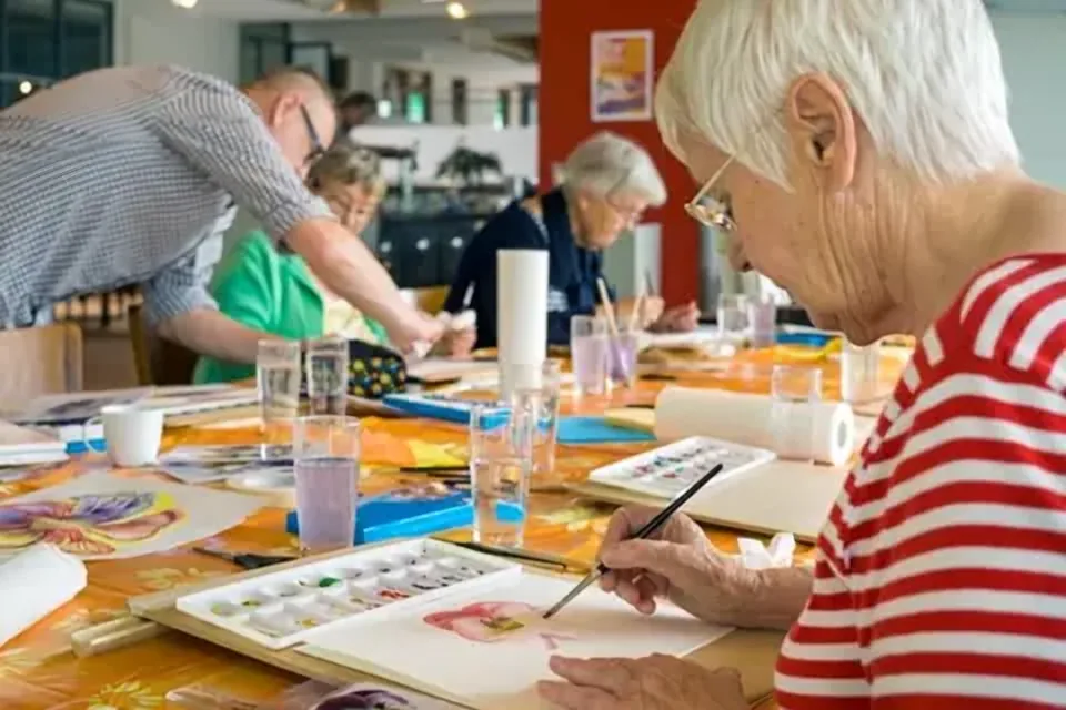 Seniorinnen und Senioren malen gemeinsam mit Wasserfarben