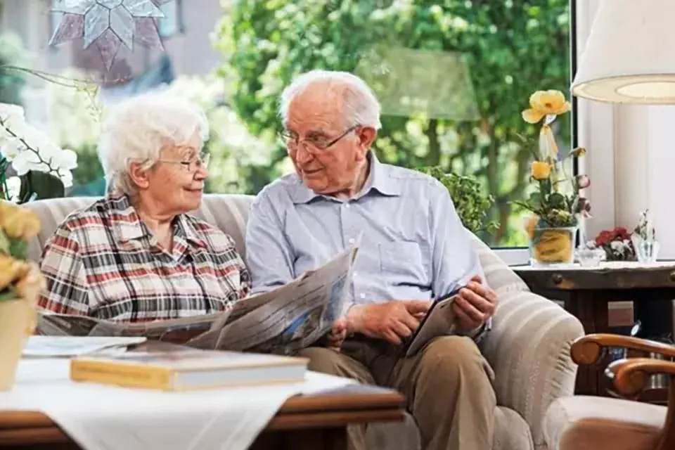 Älteres Paar liest entspannt gemeinsam auf dem Sofa