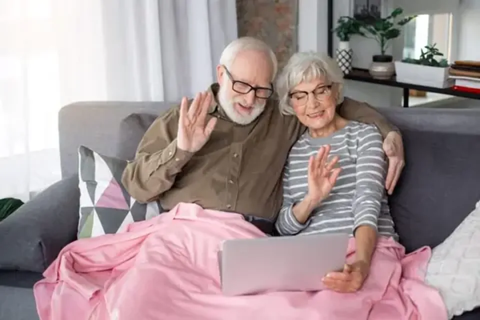 Älteres Paar winkt bei einem Videoanruf in die Kamera