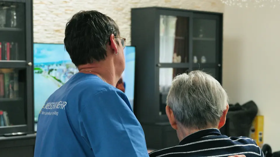 Pflegekraft von MENSCH & MEHR im Gespräch mit einem Patienten zu Hause