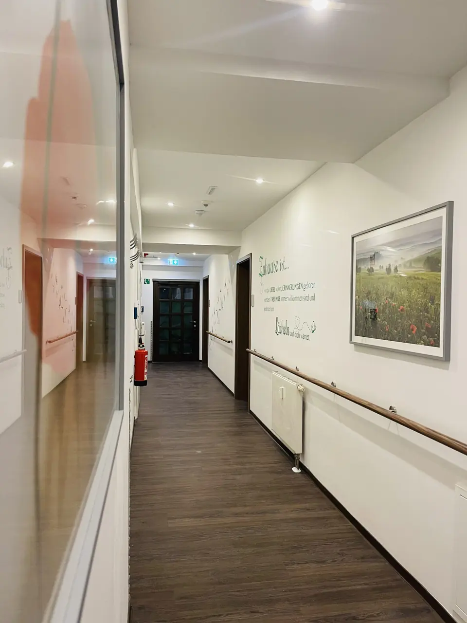 Heller Gang mit Handlauf und Bildern an der Wand